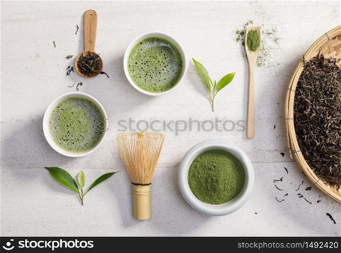 Organic matcha green tea powder in bowl with wire whisk and green tea leaf on white stone table, Organic product from the nature for healthy with traditional style