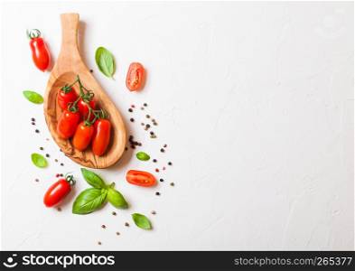 Organic Mini San Marzano Tomatoes on the Vine with basil and pepper in oilve wood plate on white background.