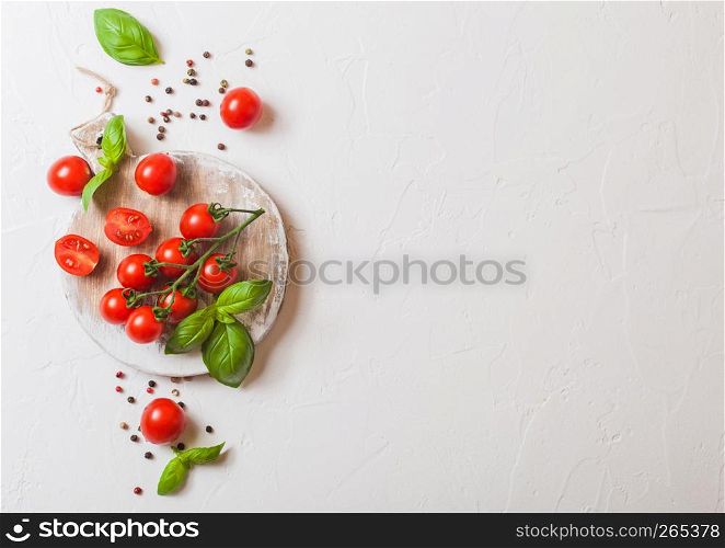 Organic Mini San Marzano Tomatoes on the Vine with basil and pepper on chopping board on white background