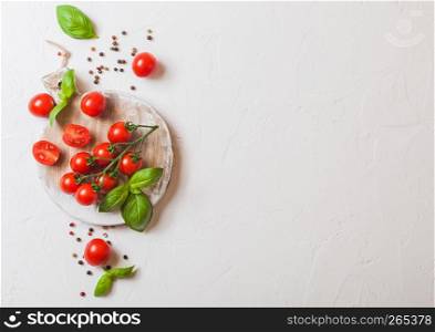 Organic Mini San Marzano Tomatoes on the Vine with basil and pepper on chopping board on white background