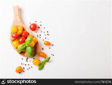 Organic Mini Tomatoes with basil and pepper in oilve wood plate on white background.