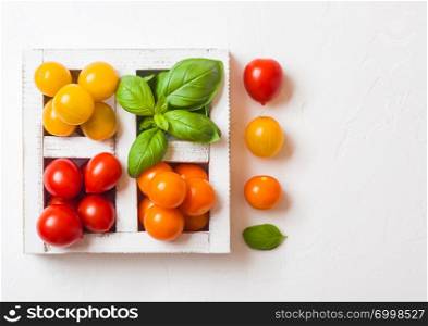 Organic Mini Tomatoes with basil and pepper in wooden box on stone kitchen background.