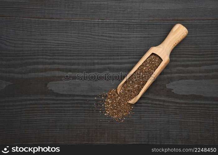 Organic natural chia seeds and wooden scoop close-up on wooden background or table. High quality photo. Organic natural chia seeds and wooden scoop close-up on wooden background or table