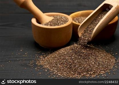 Organic natural chia seeds, bowl and wooden scoop close-up on wooden background or table. High quality photo. Organic natural chia seeds, bowl and wooden scoop close-up on wooden background or table