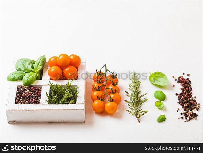 Organic Orange Rapture Cherry with basil and pepper and rosemary in white wooden box on stone kitchen background.