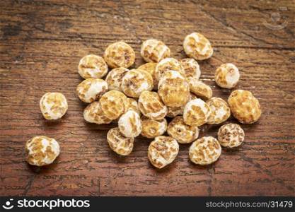organic peeled tiger nuts, a rich source of resistant starch,a small pile against rustic, weathered wood
