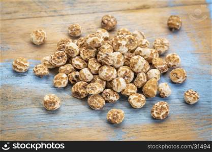 organic peeled tiger nuts, a rich source of resistant starch,a small pile against grunge wood