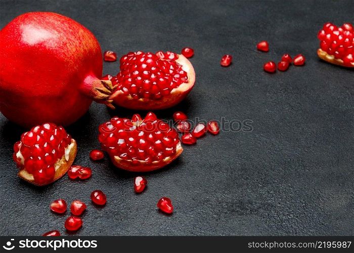 Organic Pomegranate and seeds close-up macro studio shot. Pomegranate and seeds close-up on dark concrete background