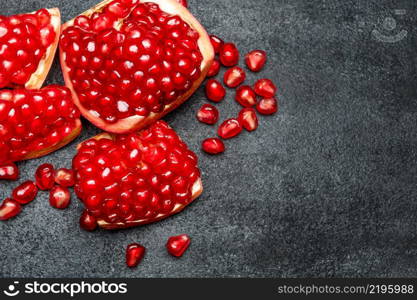 Organic Pomegranate and seeds close-up macro studio shot. Pomegranate and seeds close-up on dark concrete background