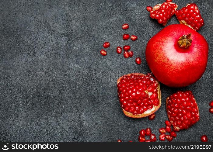 Organic Pomegranate and seeds close-up macro studio shot. Pomegranate and seeds close-up on dark concrete background