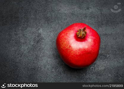 Organic pomegranate on dark concrete background. Studio shot. Pomegranate isolated dark background