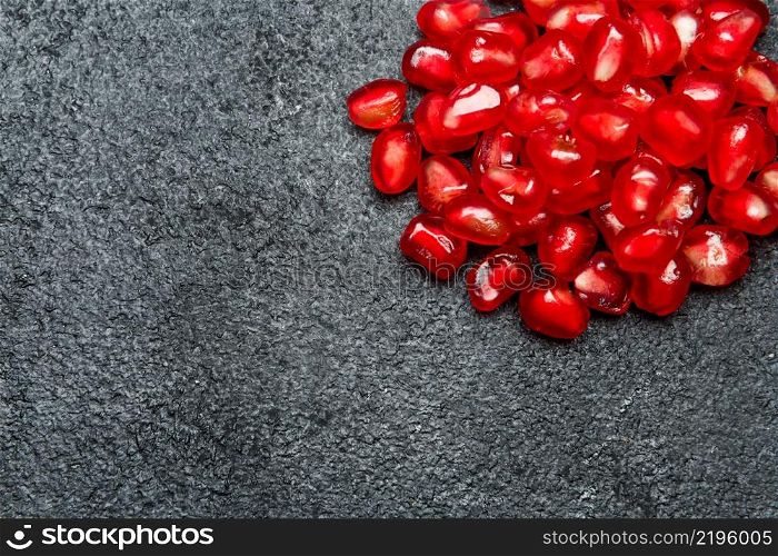 Organic Pomegranate seeds close-up macro studio shot. Pomegranate seeds close-up on dark concrete background