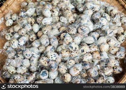 Organic quail eggs packed for sale at outdoor asian marketplace. Food background