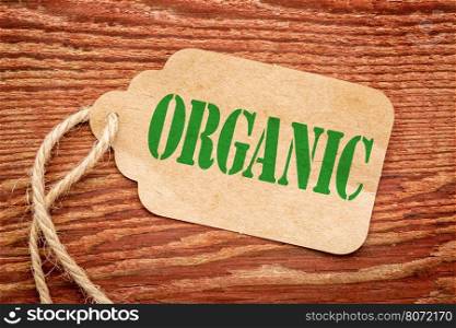 organic sign a paper price tag against rustic red painted barn wood - shopping and healthy lifestyle concept