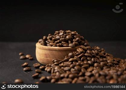 Organic toasted coffee beans on rustic black stone table with copy space for your text on black background