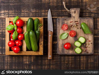 Organic Tomatoes and cucumber with basil and linen towel in vintage wooden box on wooden table