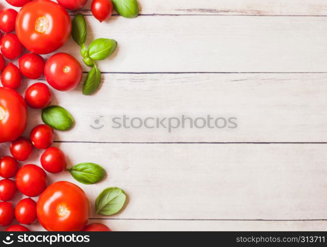 Organic Tomatoes on the Vine with basil on white kitchen woden background