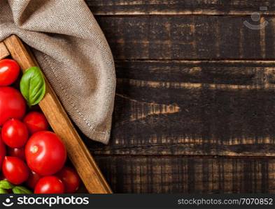 Organic Tomatoes with basil and linen towel in vintage wooden box on wooden table