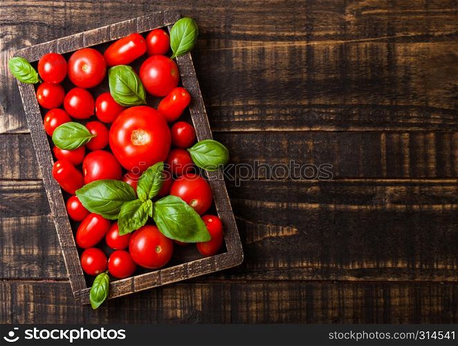 Organic Tomatoes with basil and pepper in vintage wooden box on wooden table