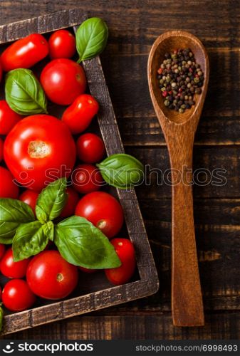 Organic Tomatoes with basil and pepper on spoon in vintage wooden box on wooden table