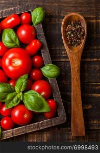 Organic Tomatoes with basil and pepper on spoon in vintage wooden box on wooden table