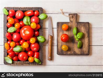Organic Tomatoes with basil in vintage box on chopping board on wooden kitchen background.