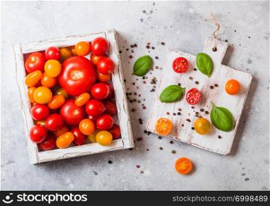 Organic Tomatoes with basil in vintage wooden box on stone kitchen table