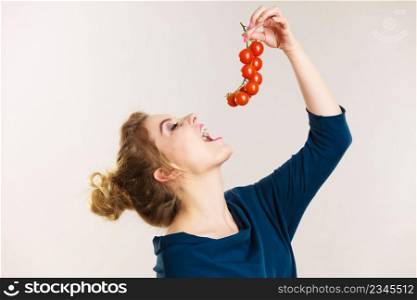 Organic vegetables and food concept. Happy positive smiling woman holding eting fresh cherry tomatoes. Woman holding eating fresh cherry tomatoes