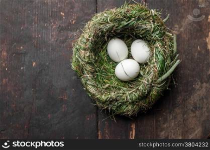 Organic white eggs in hay nest at wooden table. Eco food composition in rural vintage style
