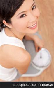 Oriental Asian Chinese Woman Weighing Herself on Scales at Gym