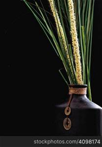 Oriental Vase with assorted grasses on a black background.