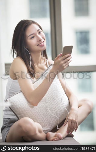 Oriental woman listening to music on her mobile phone