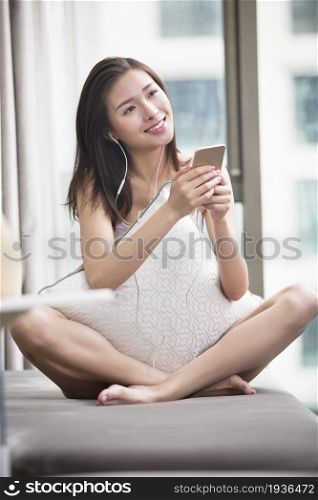 Oriental woman listening to music on her mobile phone