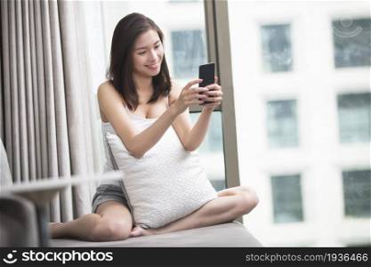 Oriental woman play mobile phone at home