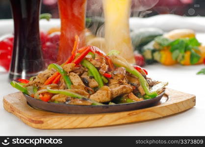 original fajita sizzling smoking hot served on iron plate ,with selection of beer and fresh vegetables on background ,MORE DELICIOUS FOOD ON PORTFOLIO