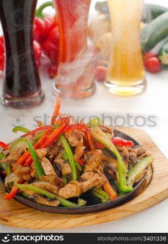 original fajita sizzling smoking hot served on iron plate ,with selection of beer and fresh vegetables on background ,MORE DELICIOUS FOOD ON PORTFOLIO