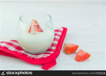 Original flavor yogurt with fresh strawberry in clear glass on white wood background