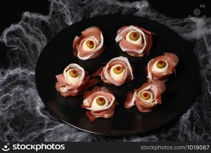 Original Halloween snacks. Eyeballs cooked from ham with mozzarella, olives stuffed with red pepper