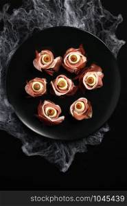 Original Halloween snacks. Eyeballs cooked from ham with mozzarella, olives stuffed with red pepper