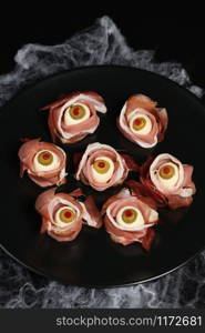 Original Halloween snacks. Eyeballs cooked from ham with mozzarella, olives stuffed with red pepper