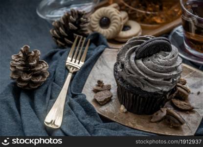 Orio cupcake with a cup of Fruit tea on a deep blue fabric. Oblique view from the top.