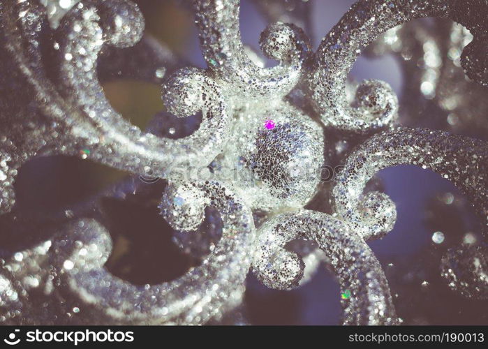 Ornamental silver snowflake glittering on fresh white snow, filtered retro colors.