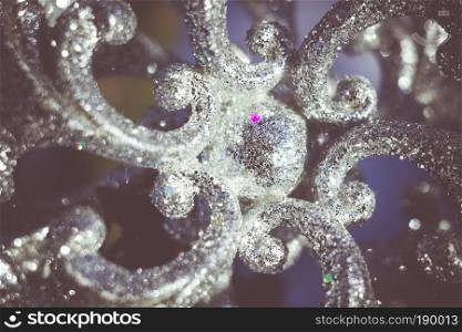 Ornamental silver snowflake glittering on fresh white snow, filtered retro colors.