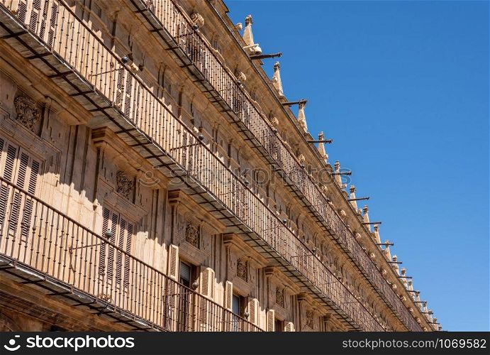 Ornate balconies and stone carvings around the windows and doors of apartments in Plaza Mayor in Salamanca. Shutters and balconies line the apartment buildings in Plaza Mayor in Salamanca