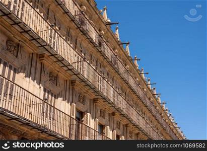 Ornate balconies and stone carvings around the windows and doors of apartments in Plaza Mayor in Salamanca. Shutters and balconies line the apartment buildings in Plaza Mayor in Salamanca