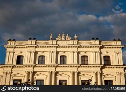 Ornate statues decorate the roof of an old building near Old Town in Warsaw at sunset