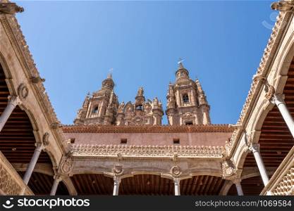 Ornate stone carvings on the Casa de la Conchas or shells around the courtyard with Clericia church in Salamanca. Casa de la Conchas and its carved balconies with Clericia church in Salamanca Spain