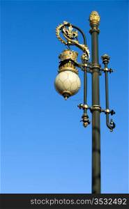 Ornate street lamp isolated on a blue sky, located in front of the Royal Palace in Madrid, Spain.