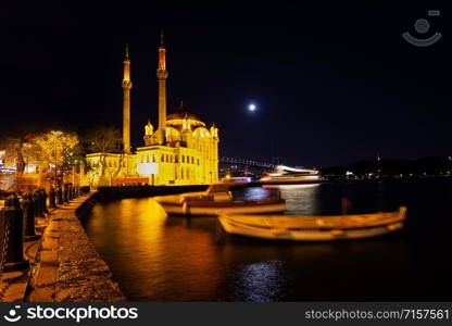 Ortakoy Mosque and embankment with swinging boats on the background of the Bosphorus Bridge at night. Istanbul, Turkey. Ortakoy Mosque and embankment with swinging boats on background of Bosphorus Bridge at night