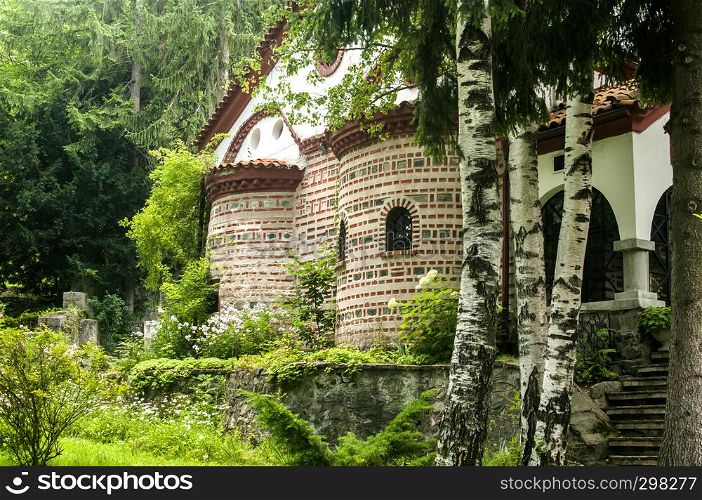 Orthodox medieval byzantine style church facade and green monastery garden